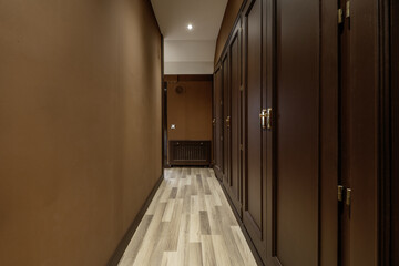 Hallway to a dressing room with access to numerous built-in wardrobes with brown wooden doors and light wooden flooring