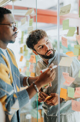Diverse group brainstorming, collaborating and sharing ideas in an office space with glass wall....