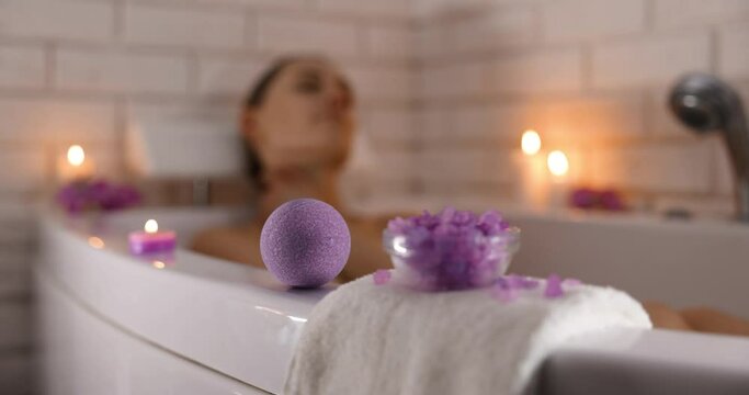 home spa. woman relaxing in bathtub in candle light and using bath bomb and sea salt crystals for body skin moisturizing