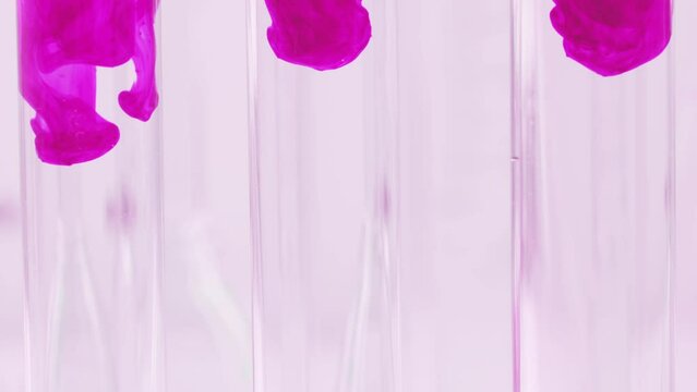 Pink liquid substance flows through a glass flask. Concept for advertising perfume and cosmetic products. Mixing pink ink with water in a large laboratory glass test tube.