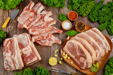 Raw pork ribs with spices and sliced raw meat on wooden background