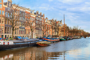 Obraz premium Cityscape on a sunny winter day - view of the water canal in the historic center of Amsterdam, the Netherlands
