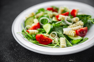 pasta salad fusilli pasta, cucumber, tomato, green lettuce, onion eating appetizer meal food snack on the table copy space food background rustic top view