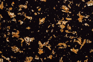 Golden glitter holiday background. Shining golden glitter on black background. Christmas, New year, event, holiday concept. Glitter background for template and design