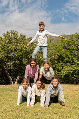 Children forming a human pyramid. Group of boys and girls in the park doing acrobatic exercises....