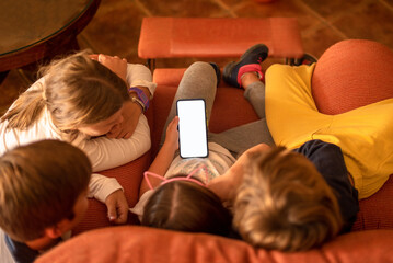 Four children looking at content on a mobile phone. Children and addiction to new technologiess. Child dependency on screens and electronic devices - obrazy, fototapety, plakaty