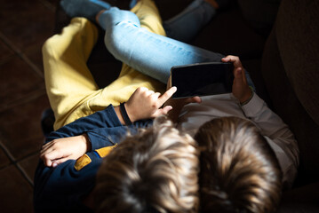 Two children lying on the couch, staring at a mobile phone. Addiction and dependence of children and youth on new technologies Parents' concern about children's obsession with consuming online content