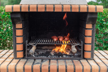 Brick barbecue with sausages sizzling over the fiery charcoal. Party and celebration with friends