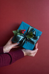 Christmas or New Year blue gift box in woman's hands. Winter holiday greeting concept