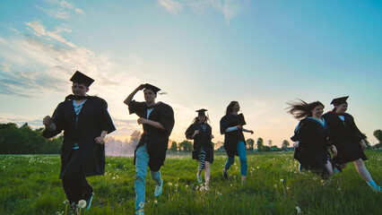 College graduates run off into the sunset in black robes.
