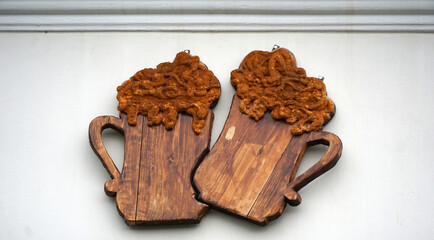 Two wooden beer jugs ,emblem on a wall of a pub - 668749410