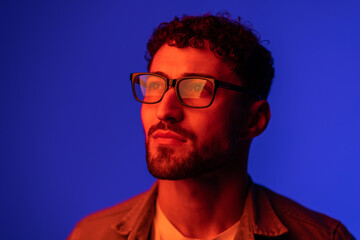 Obraz premium Portrait of young handsome man looking away against gradient purple background in neon light.