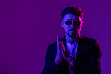 Portrait of man in shirt and glasses on colorful neon light background.