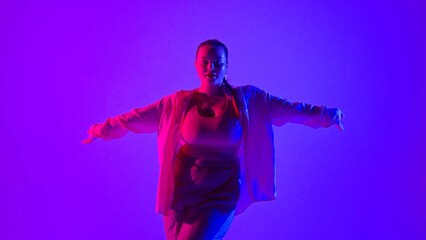 Obraz premium Attractive woman dancing jazz-funk in pink and blue neon light in a studio. Modern dynamic and energetic dance choreography. Medium full.