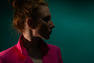 Confident, elegant lady in a pink jacket poses in a trendy studio shoot. Stylish fashion in shades of pink on a turquoise background. Attractive and beautiful showcasing urban chic.