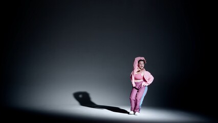 Attractive woman dancing jazz-funk in a studio. Black to white soft gradient background, white spotlight and distinct falling shadow. Modern choreography. Full length.
