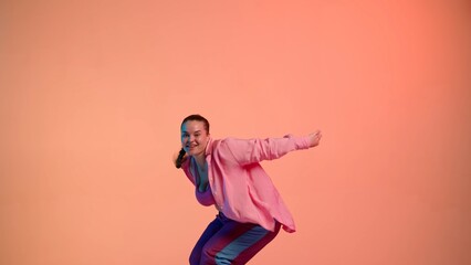 Fototapeta na wymiar Attractive woman dancing jazz-funk on pink isolated neon background in a studio. Modern dynamic and energetic dance choreography. Medium full.