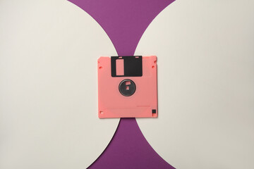 Retro 80s floppy disk on purple background with white circles. Top view