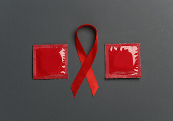Red awareness ribbon with condoms on dark background. Safe sex. Worlds HIV Aids Day