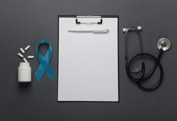 Blue ribbon symbolizing support of men and stethoscope, clipboard on dark background. Blue november...