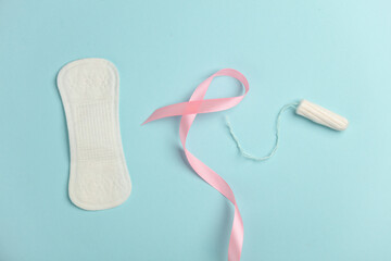 Pink ribbon, breast cancer awareness symbol with pad and tampon on blue background. Women Health