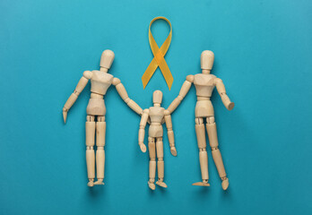 Yellow ribbon, childhood cancer awareness day symbol with wooden puppet family on blue background