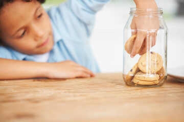 Hands, cookie jar and boy child by the kitchen counter eating a sweet snack or treat at home....