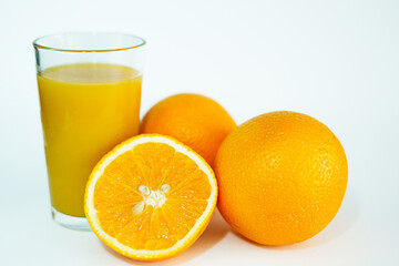 Glas of orange juice wirh oranges and cut open orange with white background.