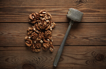 Walnuts without shells with a hammer on a wooden table