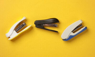 Three different staplers on a yellow background