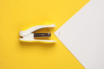 Stapler with sheets of paper on a yellow background - obrazy, fototapety, plakaty