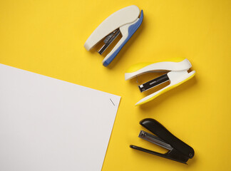 Staplers with sheets of paper on a yellow background. Business concept