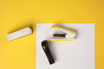 Staplers with sheets of paper on a yellow background. Business concept