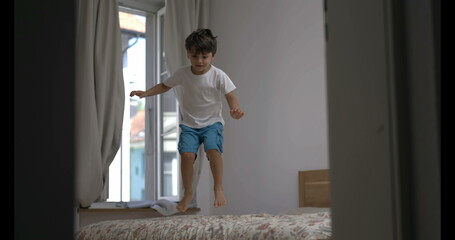Joyful child bouncing on bed in super ultra slow-motion, speed ramp in 800 fps. young boy jumping...