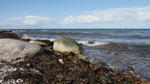 Brandung, Wellen peitschen gegen Steine am Strand der Ostsee