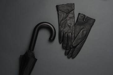 Black umbrella with leather gloves on a dark background