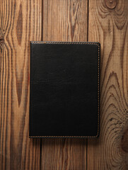 Notebook with black leather cover on wooden background
