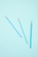 Three colored pencils in blue tones on a blue background