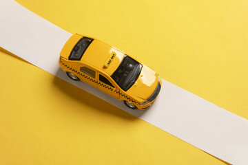 Toy model taxi car on yellow background with white tape