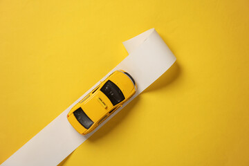 Toy model taxi car with check tape on yellow background. Top view