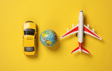 Toy taxi car model with globe and air plane on yellow background. Travel concept. Top view