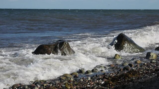 Brandung, Wellen peitschen gegen Steine am Strand der Ostsee