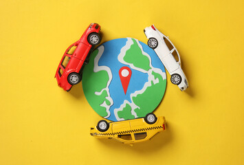 Car models with geolocation point sign and globe on yellow background. Flat lay
