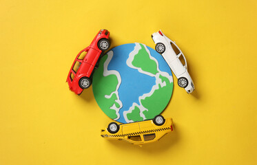 Toy cars model with globe on yellow background. Travel concept. Top view