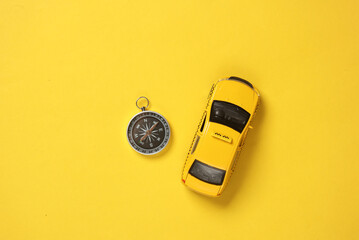Toy taxi car model with compass on yellow background. Navigation, gps