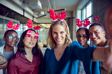 A group of diverse women take a festive selfie with reindeer antlers