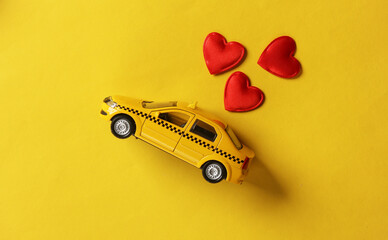 Toy taxi car model with hearts on yellow background. Love concept