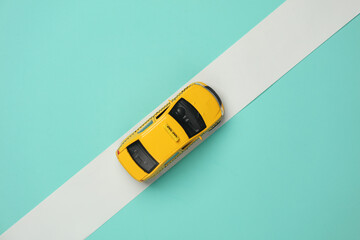 Toy taxi car model on blue background with white tape