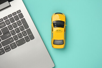 Toy taxi car model with laptop on blue background. Top view