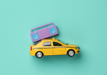 Toy taxi car model with boombox audio player on blue background. Top view